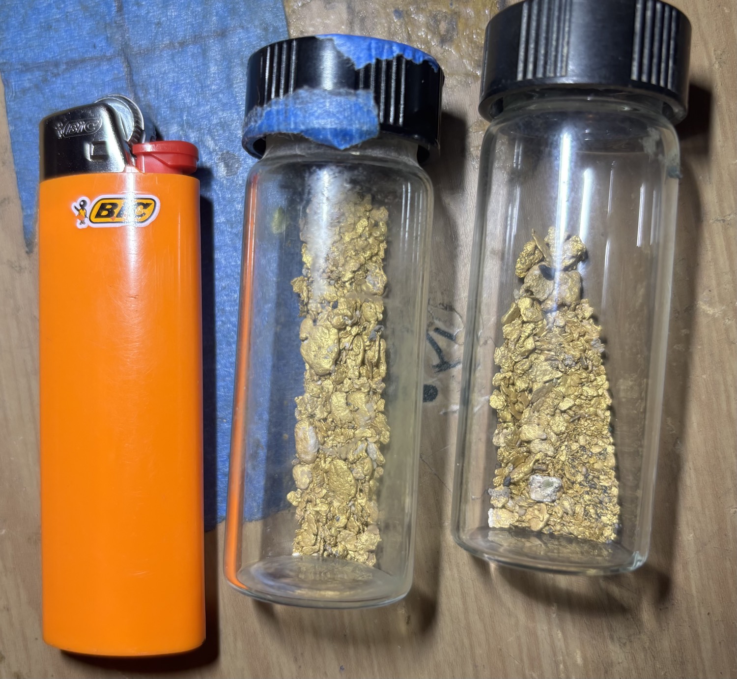 Gold concentrates in vials next to BIC lighter for scale